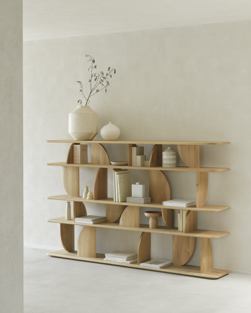 Etagère en bois avec divers objets décoratifs dont des vases, des livres et une petite plante. Les étagères présentent un design incurvé et élégant et sont finies en chêne naturel vernis. Situé dans une pièce minimaliste aux couleurs claires.