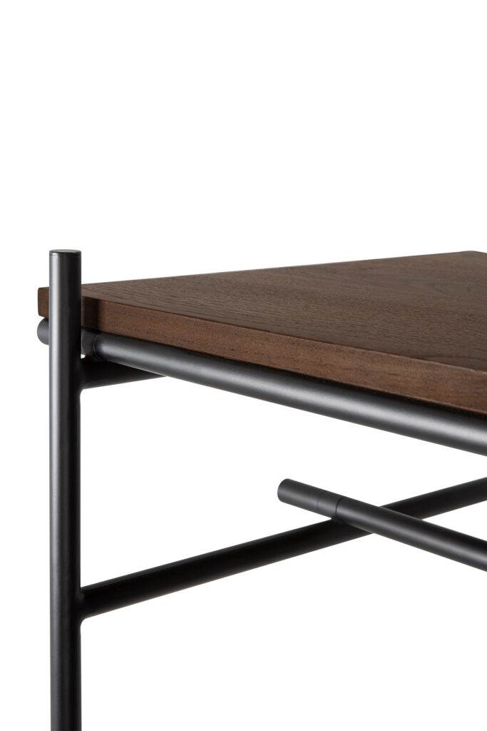 Gros plan d'un coin de table composé d'un plateau en teck vernis et d'une structure en métal noir avec supports tubulaires.