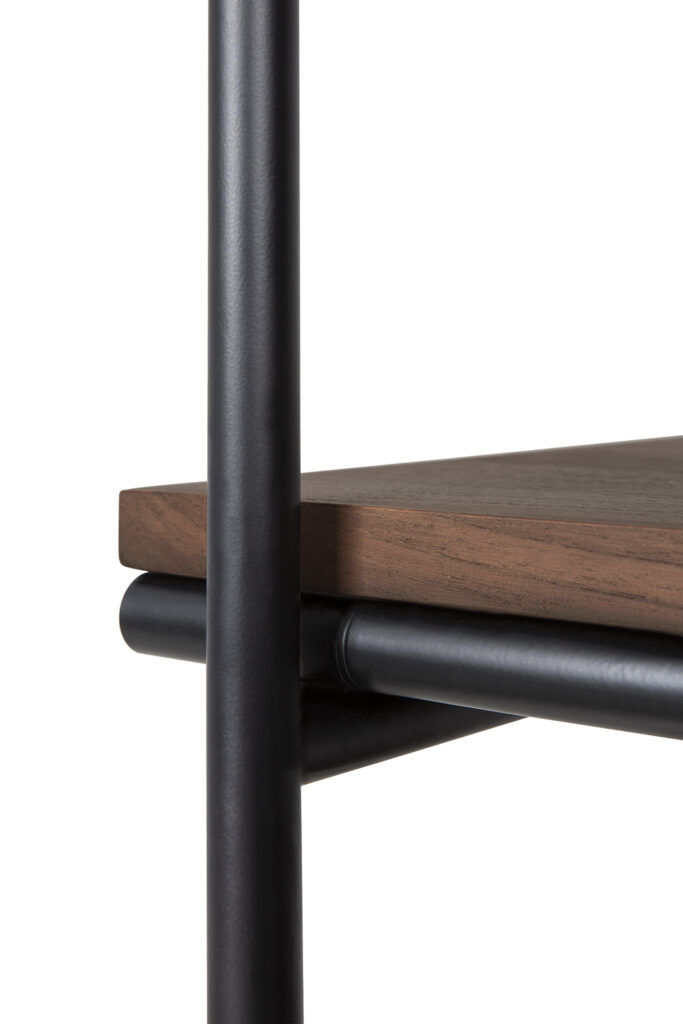 Gros plan d'une étagère en bois avec des supports en métal sombre, mettant en valeur l'intersection de la surface en teck verni et du cadre métallique vertical.