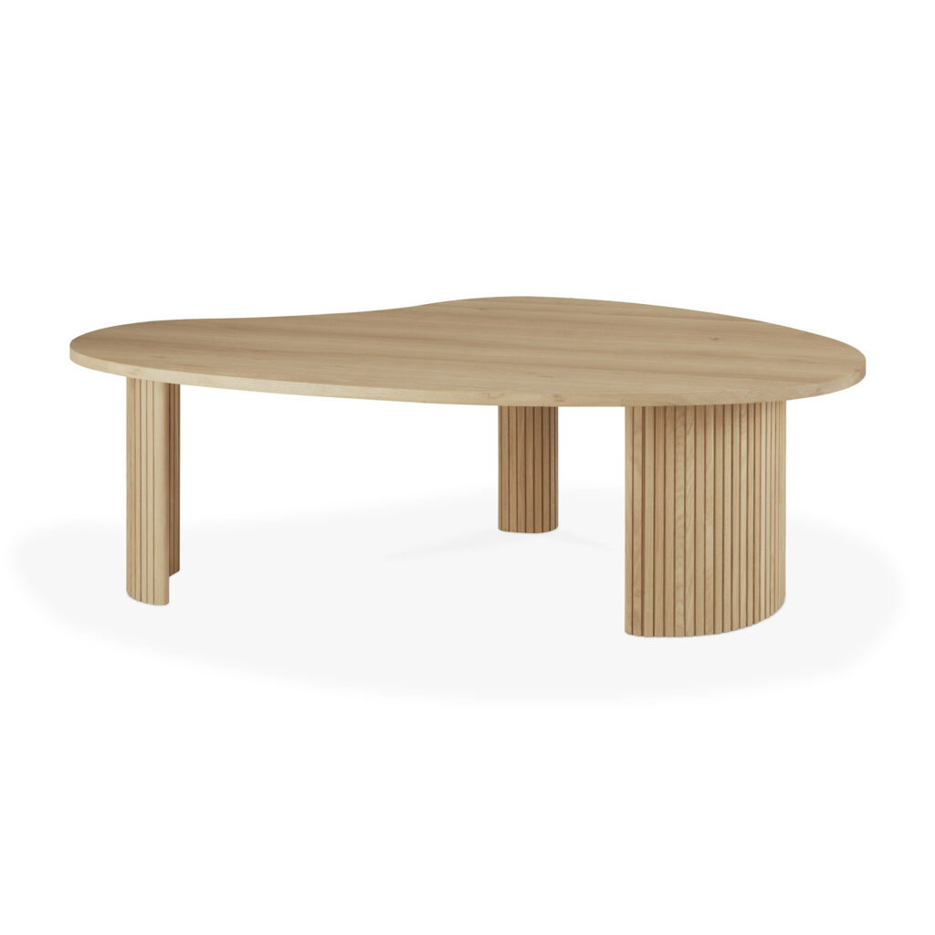 Une table basse en bois avec un plateau courbé et asymétrique rappelant un boomerang et trois pieds cylindriques, dont un nervuré, fabriqués en chêne naturel huilé.