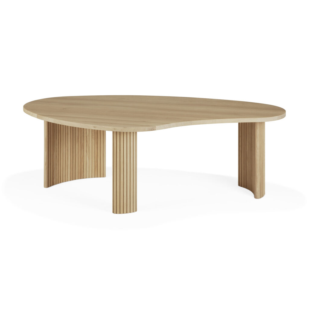 Une table basse en bois avec un plateau unique en forme de boomerang et trois pieds cylindriques nervurés verticalement, fabriqués à partir de chêne naturel huilé.