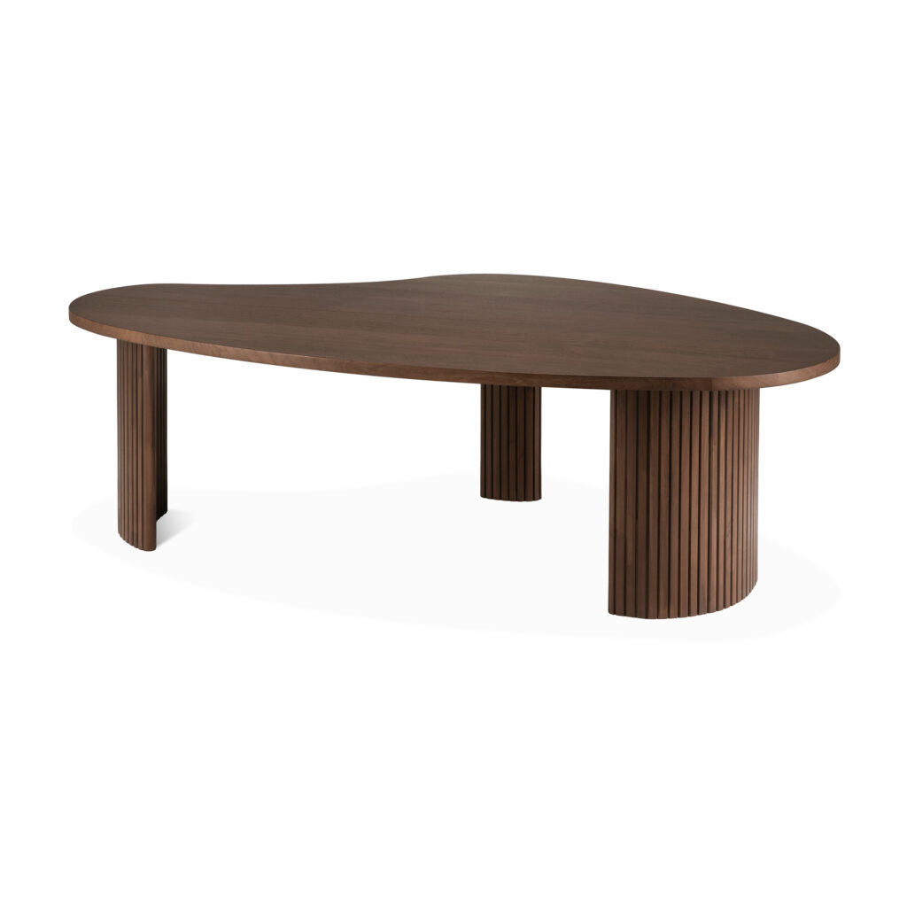 Une table basse marron asymétrique en teck teinté, dotée de trois pieds cylindriques dont l'un est courbé comme un boomerang.