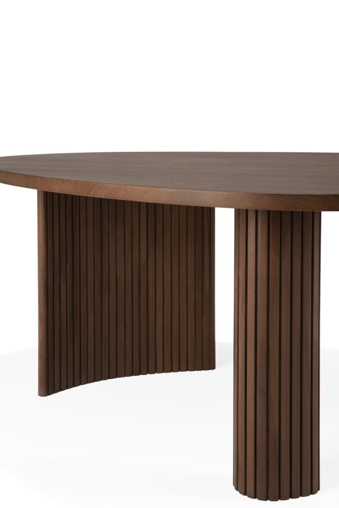 Une table basse en bois de forme ovale avec une surface lisse et deux pieds cylindriques cannelés, avec une finition teck teinté brun vernis.