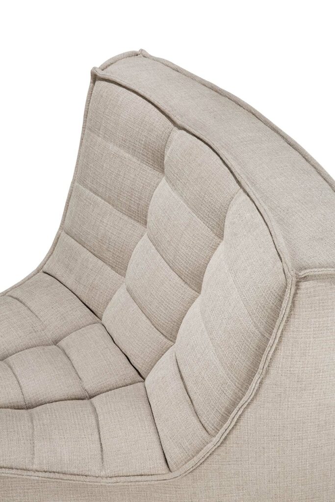 Gros plan d'un dossier de chaise rembourré en tissu beige avec un design capitonné et rembourré et des bords incurvés, rappelant l'élégant détail d'angle rond à 45° que l'on retrouve dans les canapés modulaires N701.