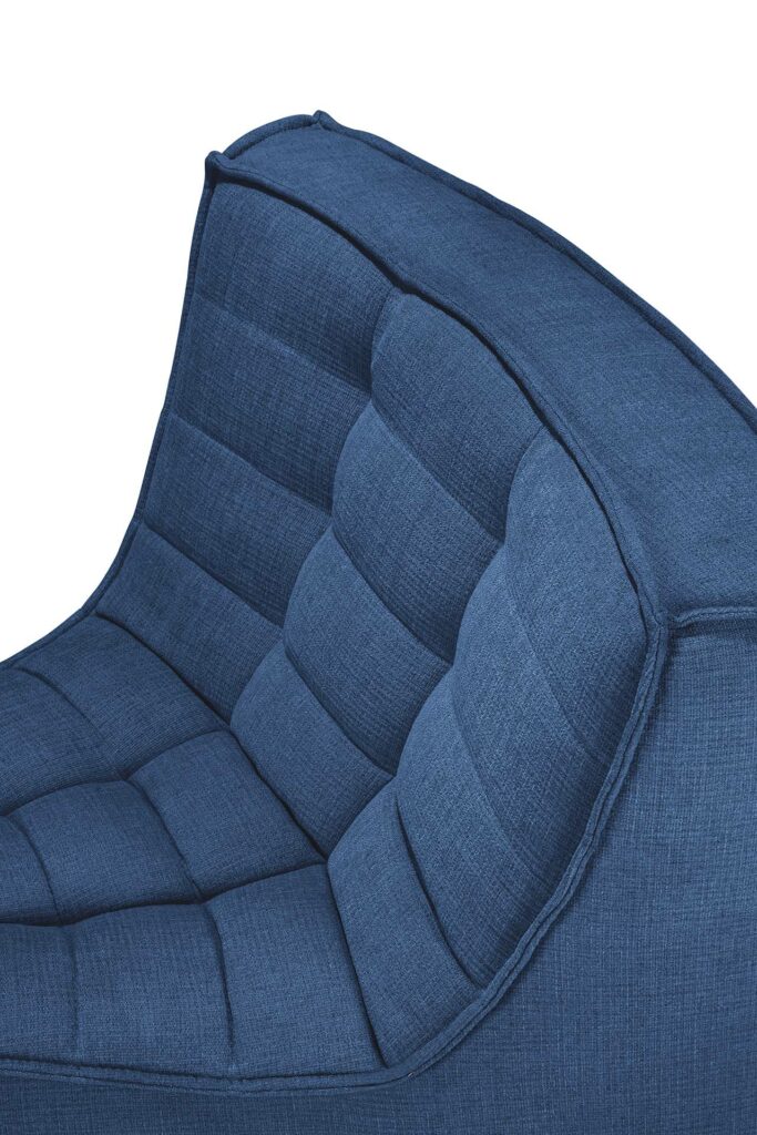 Gros plan d'une chaise bleue rembourrée avec un dossier capitonné et matelassé, complétant parfaitement votre canapé modulaire.