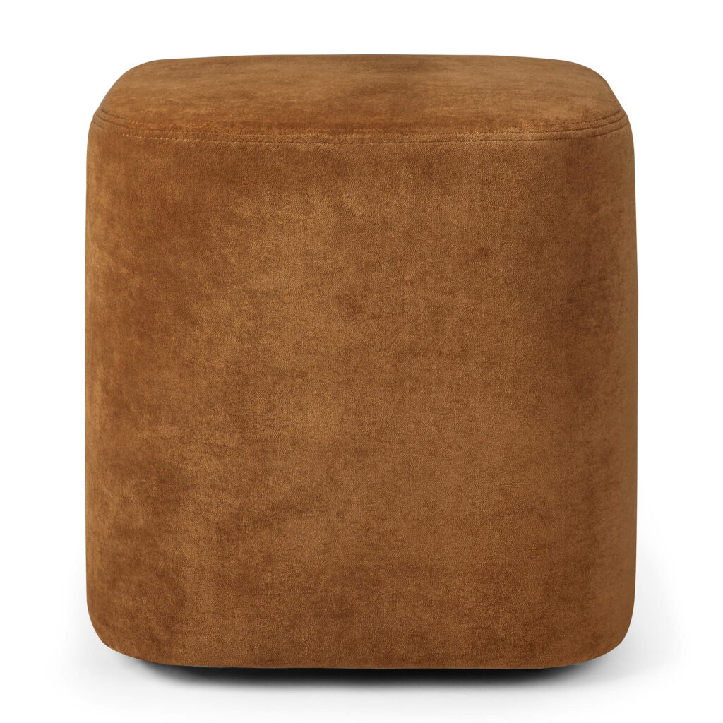 Un pouf cube en daim marron aux surfaces lisses et aux bords arrondis, avec une touche de tissu cannelle, sur un fond neutre.