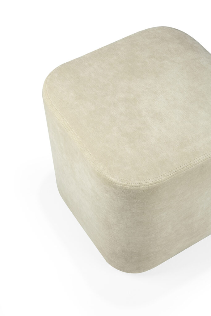 Un pouf cube beige avec des bords arrondis et une surface en tissu lisse cannelle.