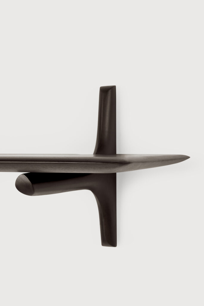 Étagère murale flottante minimaliste marron foncé avec un seul support conique, montée sur un mur blanc uni.