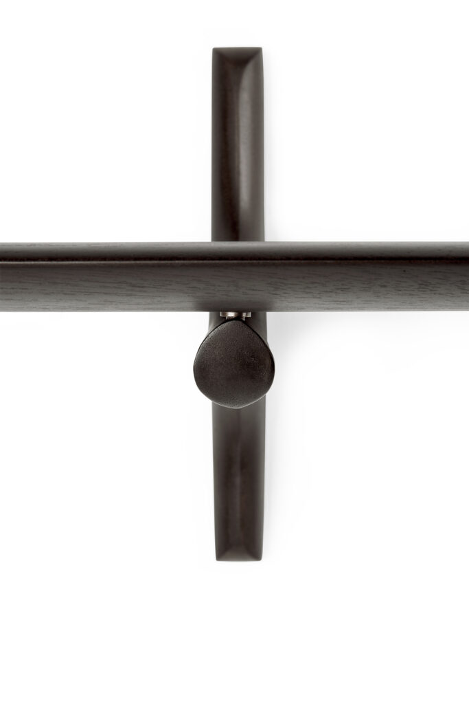 Vue rapprochée d'un crochet mural minimaliste en métal de couleur foncée monté sur un mur blanc, complétant parfaitement l'étagère murale PI.