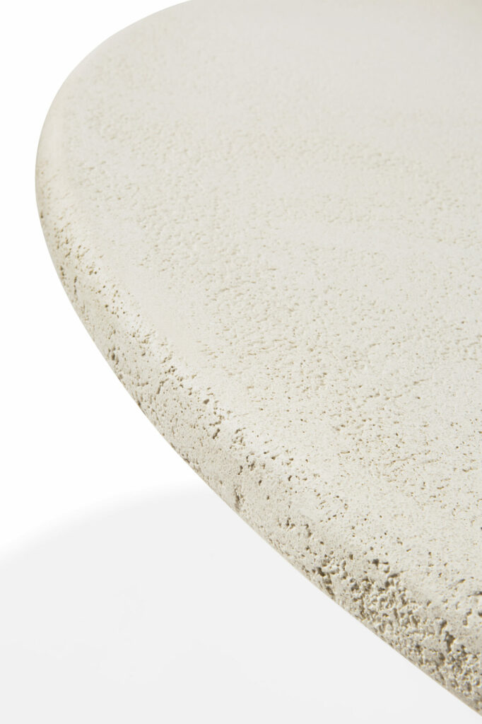 Gros plan d'un bord incurvé texturé, blanc cassé, d'une surface semblable à de la pierre sur un fond blanc, mettant en valeur les élégants éléments de table.