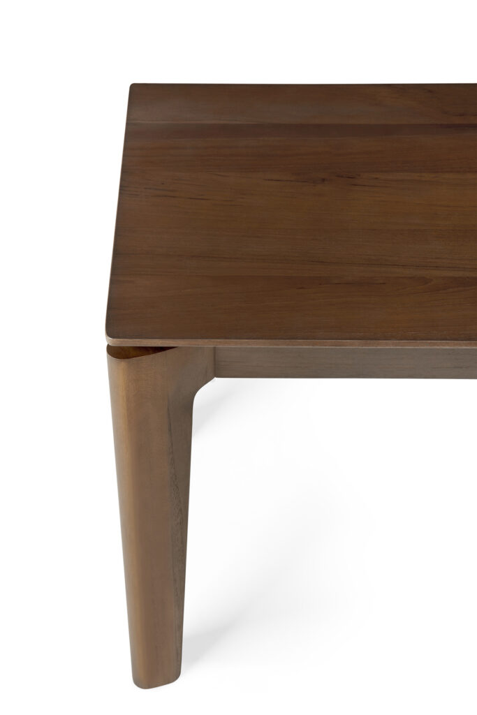 Gros plan du coin d'une table Banc Bok en teck avec pieds inclinés et finition lisse teck teinté brun vernis.