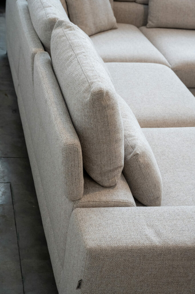 Vue latérale d'un canapé sectionnel Horizon [3,5z +L2Hz] - C50 Reserve 4192 gris clair avec revêtement texturé sur un sol en béton, mettant en valeur son élégance minimaliste. Les coussins sont soigneusement disposés.