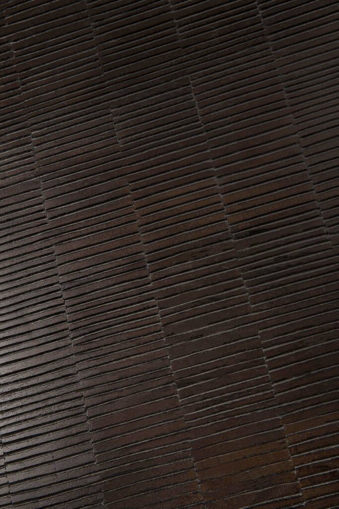 Gros plan de la table basse Grooves présentant sa surface texturée brun foncé avec des panneaux rectangulaires alignés horizontalement et des rainures distinctes.