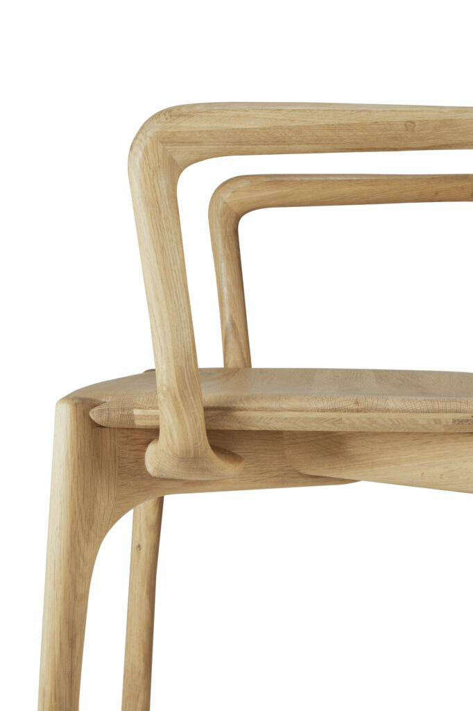 Gros plan du dossier, de l'accoudoir et de l'assise de la chaise de salle à manger PI avec accoudoir, présentant une finition en bois de couleur claire et un design minimaliste.