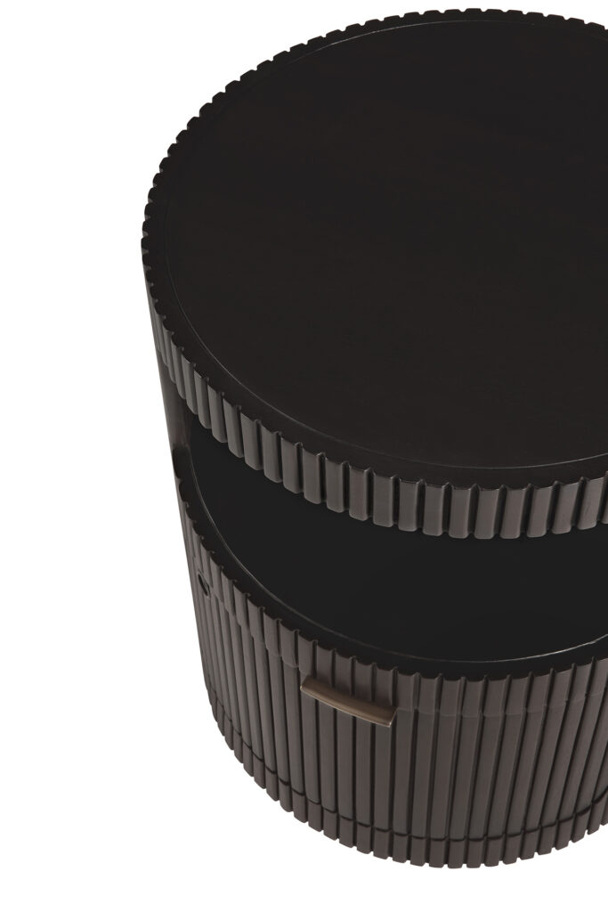 Un caisson à tiroirs Boomerang rond et de couleur foncée avec une étagère inférieure et un design extérieur nervuré, rappelant les courbes épurées d'un boomerang.