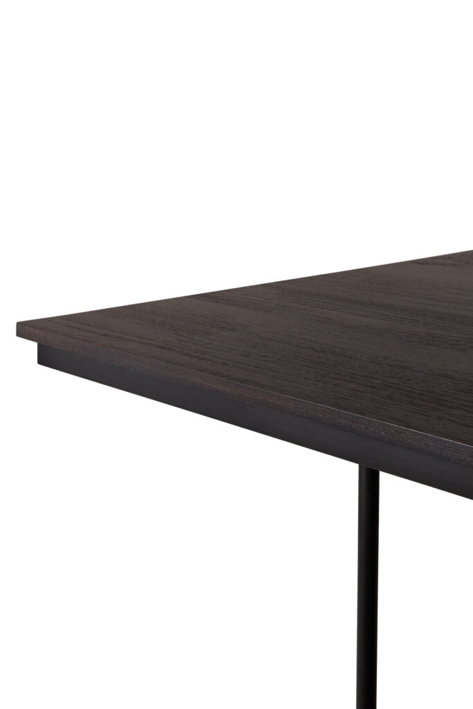 Vue rapprochée du coin de la table à manger Tacet, mettant en valeur sa surface en bois foncé complétée par un pied en métal noir élégant.