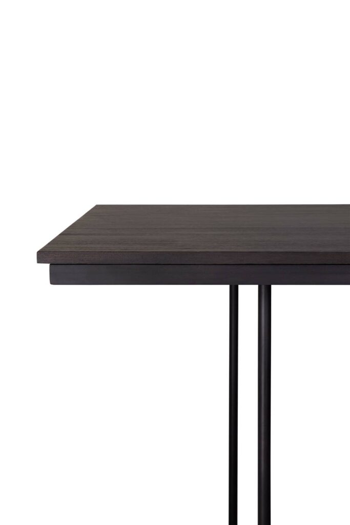 Vue rapprochée de la table à manger Tacet présentant son plateau noir rectangulaire minimaliste et ses pieds noirs élégants et fins.