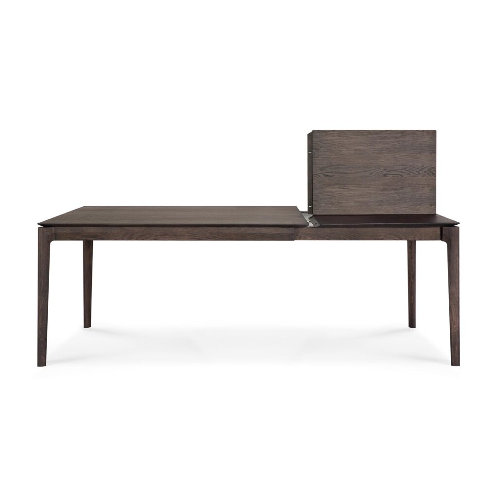 La table à manger extensible Bok 140- présente une finition moderne en bois foncé, une rallonge rectangulaire verticale attachée sur le côté droit, un design minimaliste élégant et quatre pieds fuselés.