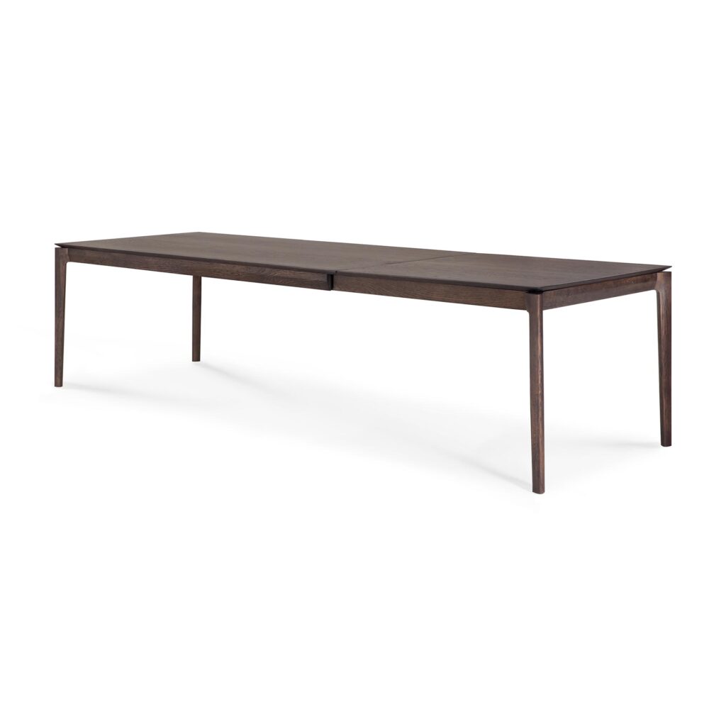 Cette longue table à manger rectangulaire extensible en bois Bok de L 200-300 présente des pieds fins et un design minimaliste. La table a une finition sombre et une surface sans couture, parfaite pour tout espace de salle à manger moderne.