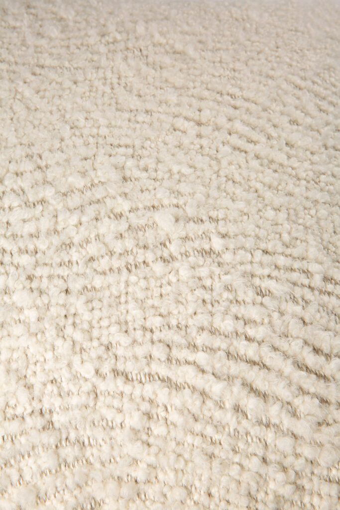 Gros plan du coussin Wave, doté d'un tissu texturé de couleur crème avec de petites boucles denses qui créent une surface douce et légèrement irrégulière, parfaite pour offrir un soutien ergonomique dans des sièges confortables.