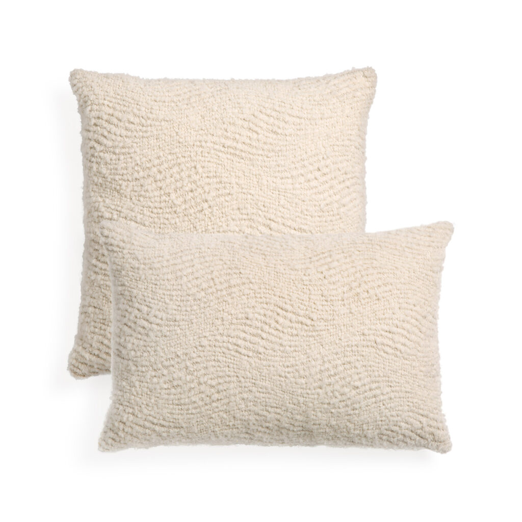 Deux coussins Wave au design blanc cassé, rectangulaire et texturé, sont empilés l'un légèrement devant l'autre sur un fond blanc.