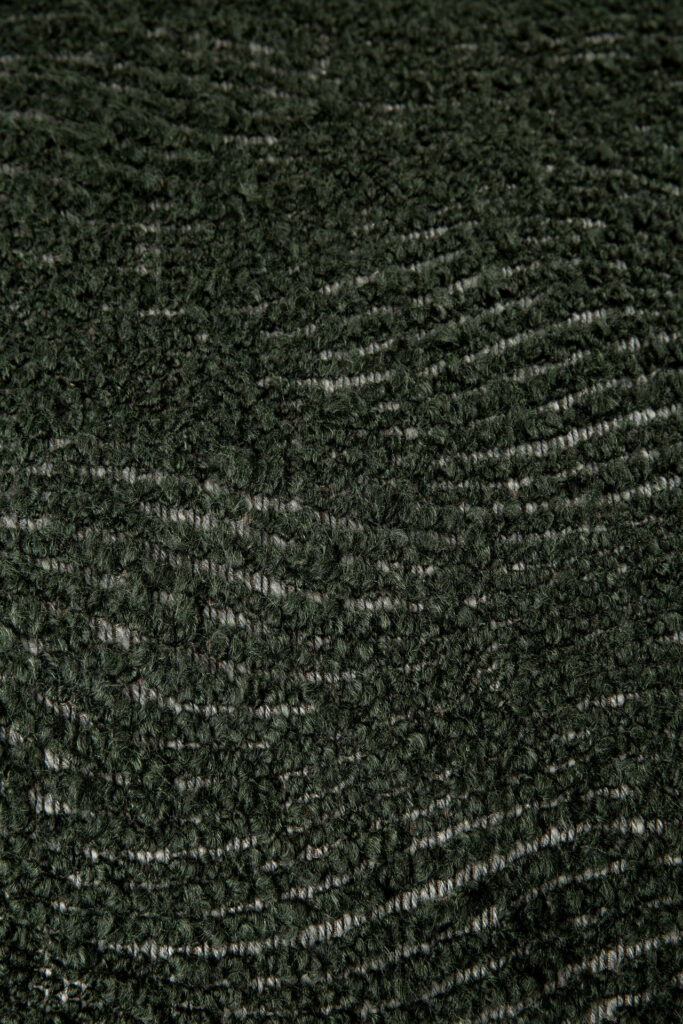 Gros plan d'un tissu texturé vert foncé présentant un subtil motif ondulé, idéal pour le coussin Wave.