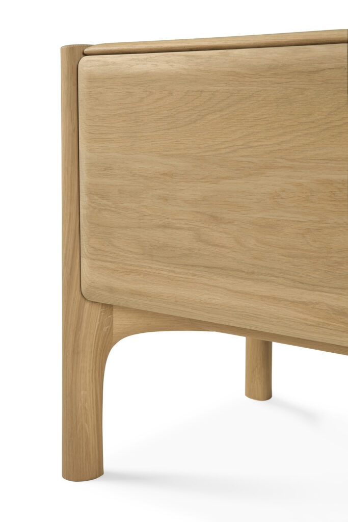 Gros plan sur le coin d'une table en bois aux bords et aux pieds arrondis. Le grain naturel du bois est visible, rappelant le chêne huilé. Le design de la table est lisse et minimaliste, s'associant parfaitement aux meubles TV PI ou à d'autres meubles TV élégants.