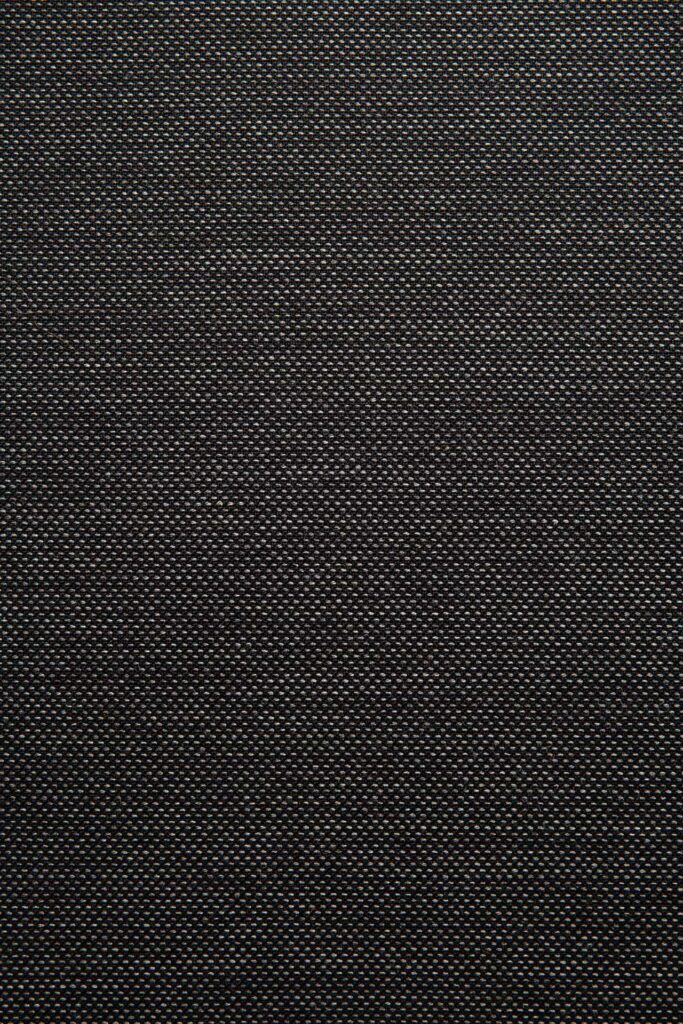 Gros plan d'une surface noire texturée avec un motif quadrillé, rappelant le tissu gris, affichant un maillage fin de petits points régulièrement espacés.