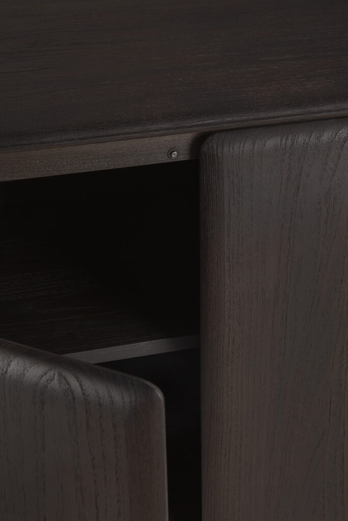 Gros plan du Buffet PI en teck 2 portes en bois foncé, montrant ses portes ouvertes et son intérieur vide avec une texture de grain de bois de teck visible sur la surface.