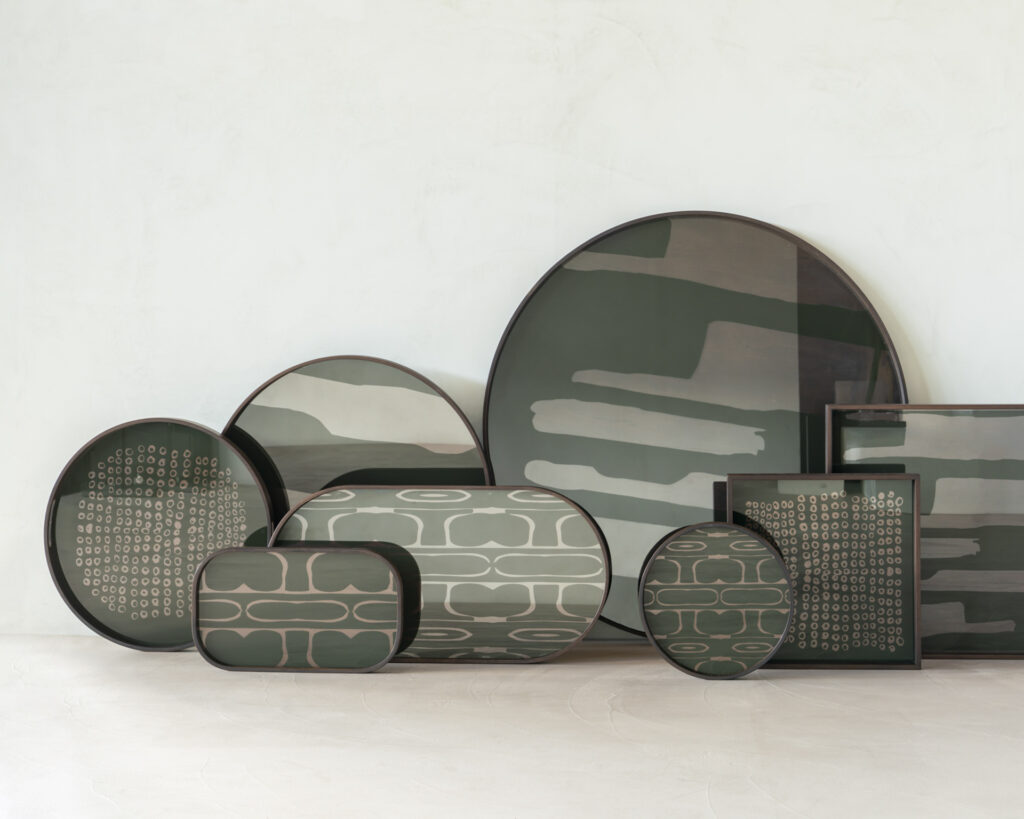 Un plateau en verre rond nommé "Seconde Nature Moss - Glass Tray - round - L", présentant des motifs abstraits verts et beiges sur un fond uni de couleur claire.