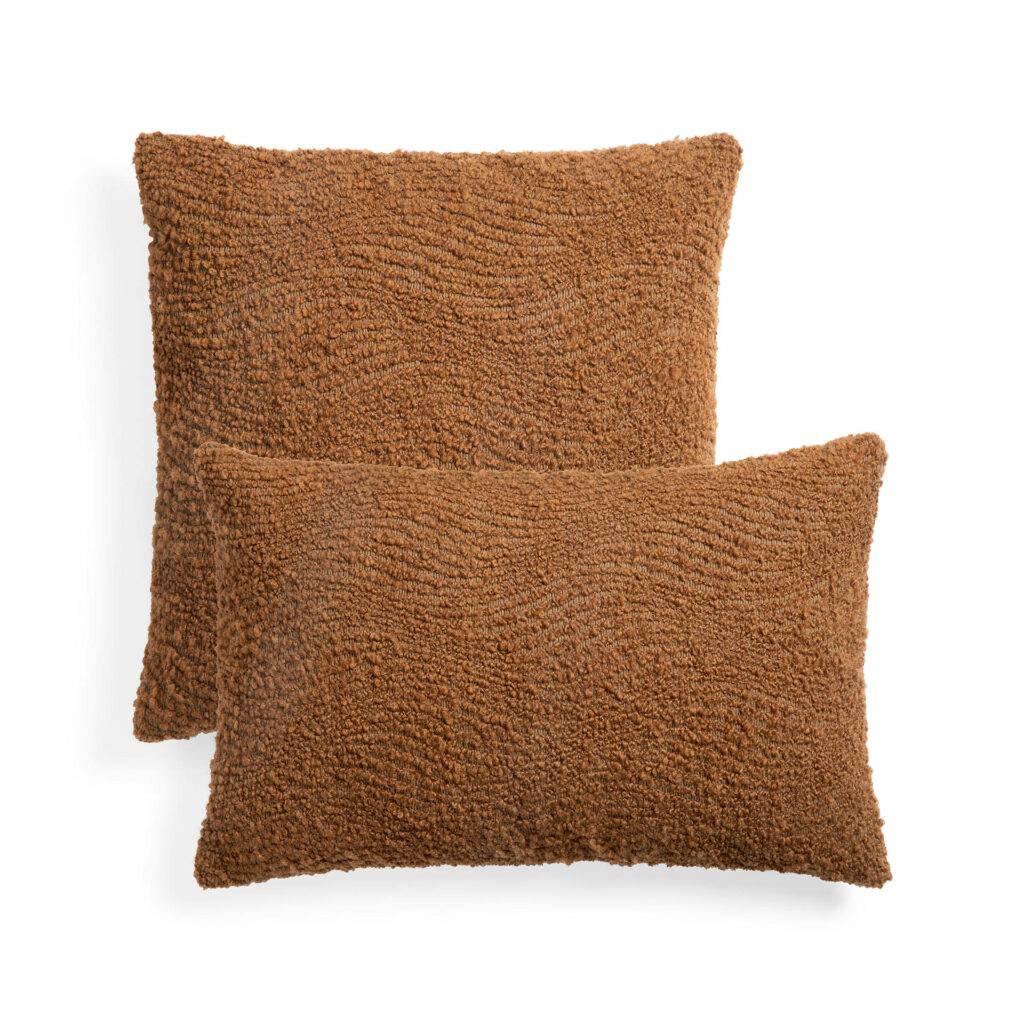 Deux coussins sherpa rectangulaires marron de tailles différentes, rappelant les coussins cannelle, sont disposés sur un fond blanc.