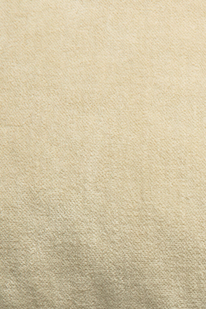 Gros plan d'une surface en tissu texturé beige, montrant un motif tissé subtil rappelant la cannelle, parfait pour un coussin en velours 50x50x15.