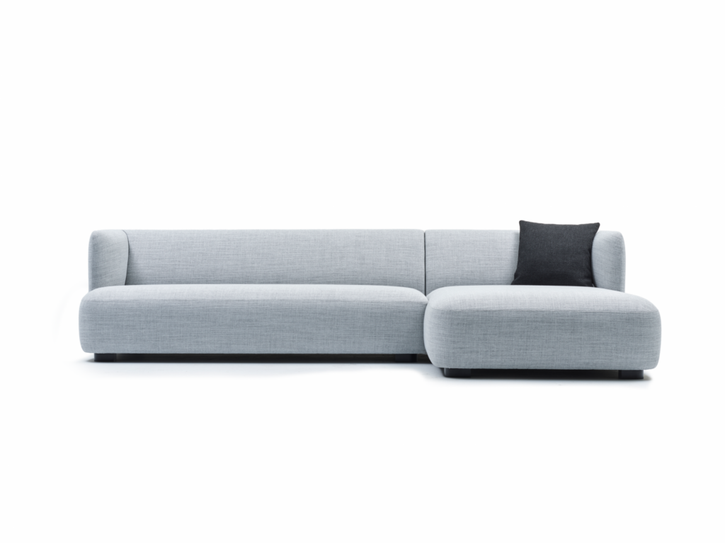 Un canapé sectionnel Canapé Ryan gris clair en forme de L (modèle : 230+712+105 - tissu 900.65) avec un seul coussin gris foncé, fabriqué à partir de tissu de qualité supérieure, sur un fond blanc uni.