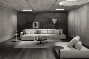 Un salon minimaliste aux murs en béton présente un canapé sectionnel, une chaise longue et deux luminaires géométriques fixés au mur. La pièce conserve un design moderne et monochrome.