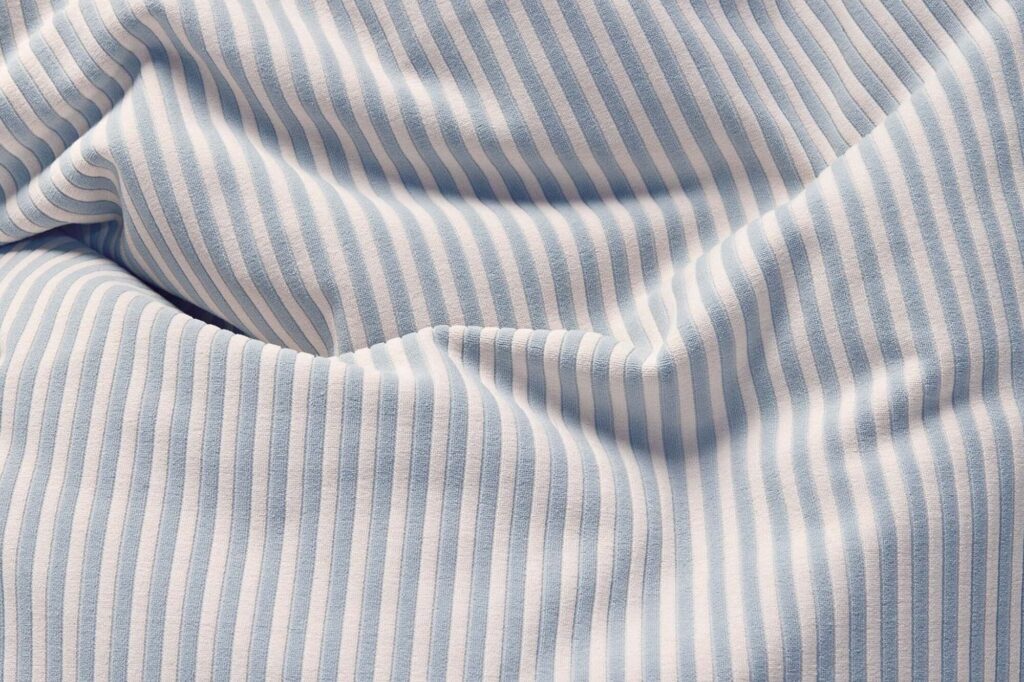 Gros plan d'un tissu Slim Terry froissé avec des rayures verticales bleu Blizzard et blanches.