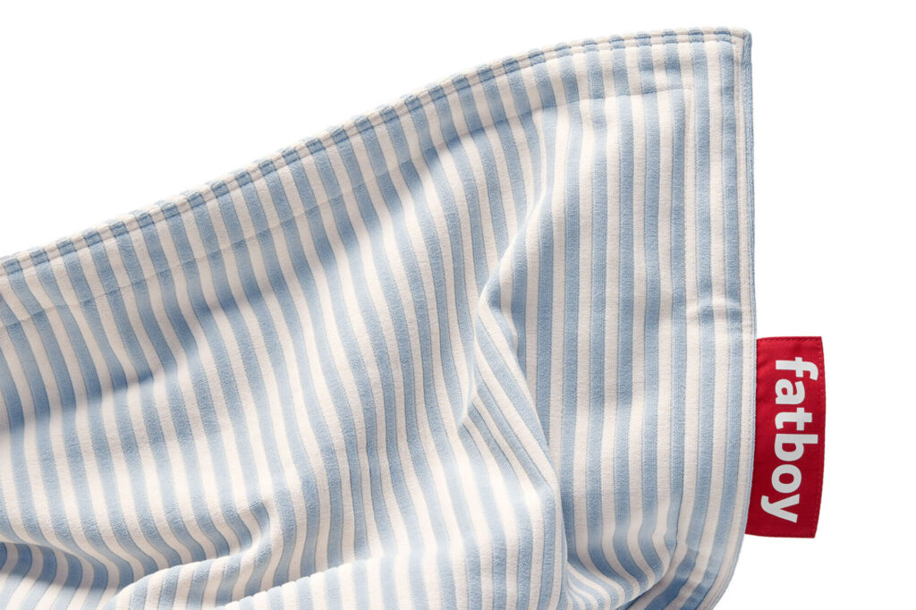 Gros plan d'un tissu rayé bleu crème et blanc Blizzard avec une étiquette rouge étiquetée « fatboy ».