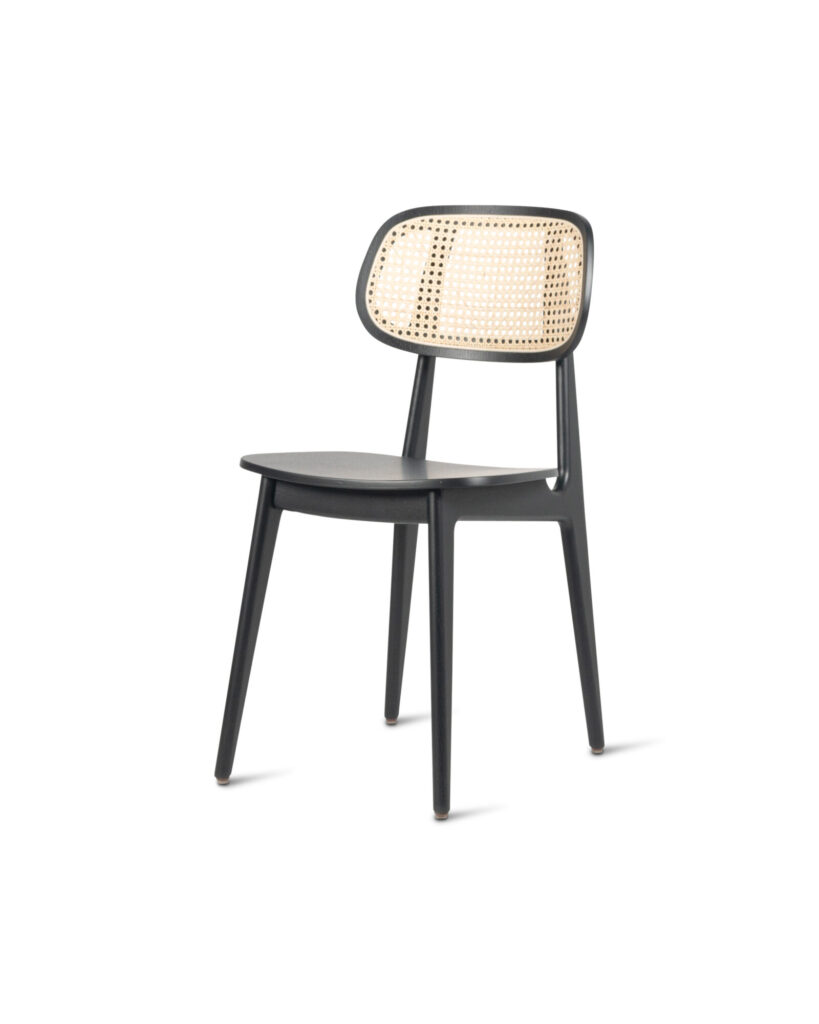 La Chaise Titus présente un cadre noir avec un dossier en rotin tressé et un siège noir massif, magnifiquement complété par du chêne teinté noir, incarnant l'élégance moderne.