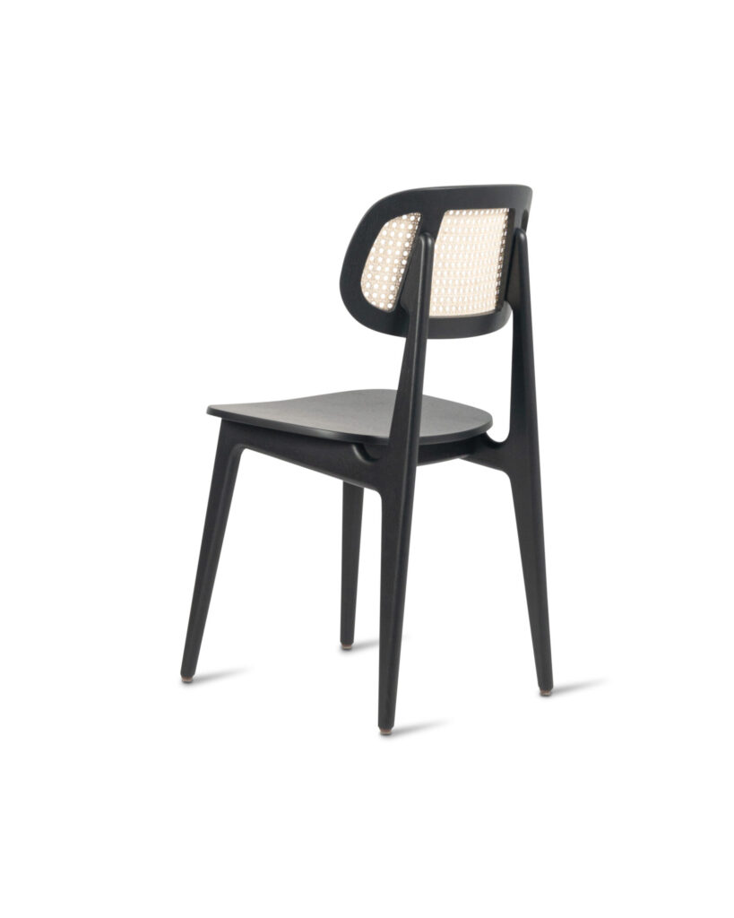 Une chaise longue noire moderne avec un dossier en rotin, légèrement incliné vers l'arrière pour mettre en valeur son design élégant et ses pieds profilés fabriqués en chêne teinté noir.