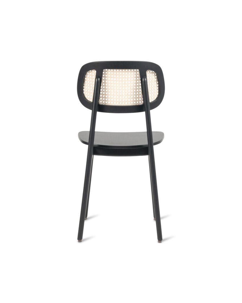 La Chaise Titus est dotée d'un dossier tressé, présenté de l'arrière sur un fond blanc éclatant, sa structure élégante mise en valeur par des contours en chêne teinté noir.