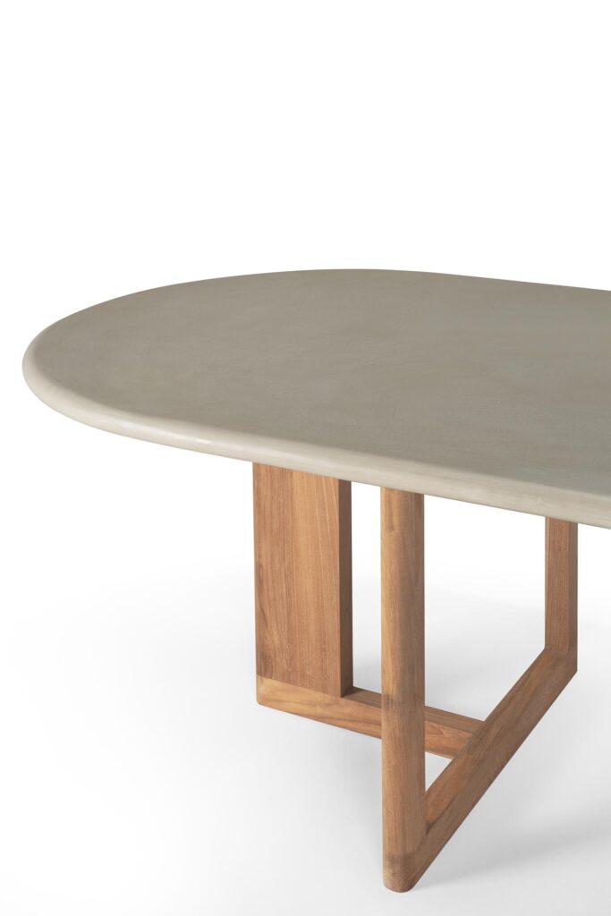La table à manger d'extérieur Trestle présente un design contemporain avec un plateau ovale lisse de couleur claire et des pieds en tréteaux en bois.