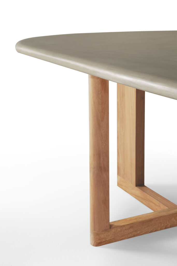 Gros plan de la table à manger d'extérieur Trestle avec une surface lisse gris clair et des pieds en bois inclinés.