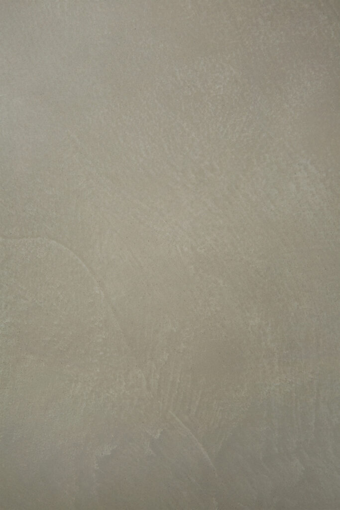 Gros plan d'un mur texturé gris clair avec de subtiles variations de nuances et des coups de pinceau visibles, créant une toile de fond idéale pour la table à manger d'extérieur ovale Canyon.