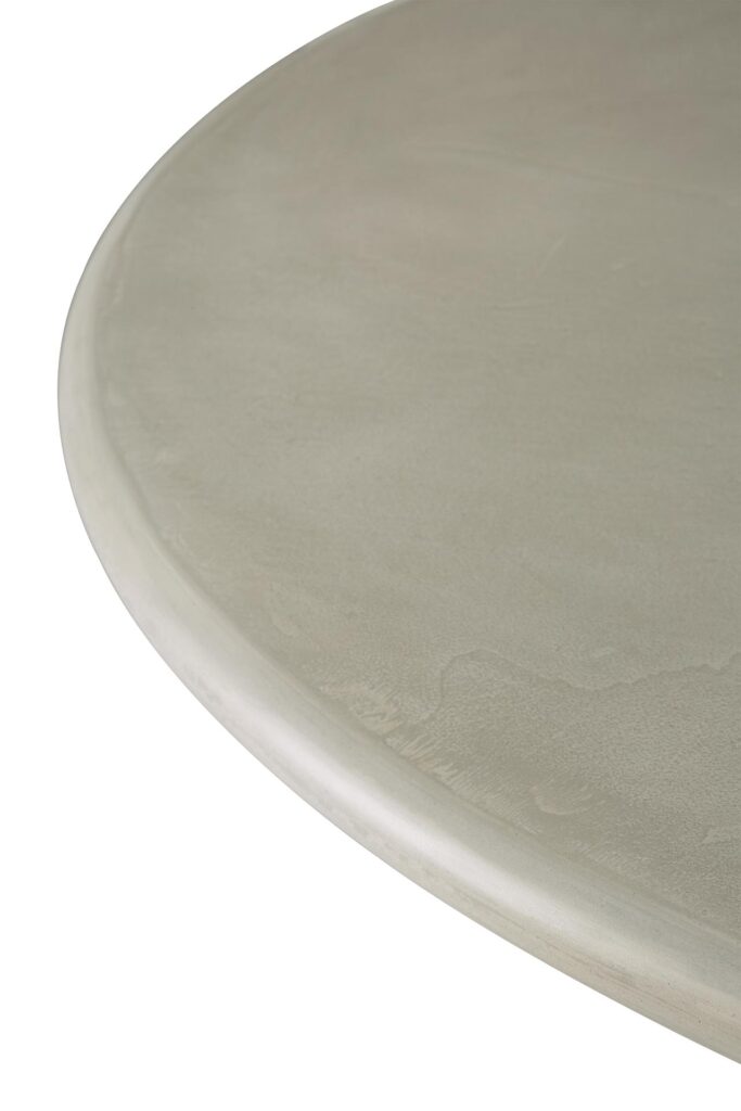 Gros plan d'une table à manger ronde et lisse avec une finition mate gris clair et une texture subtile, évoquant le design élégant de la table à manger Roller Max out.