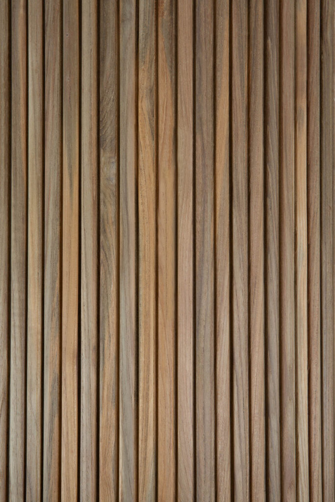 Les lattes de bois verticales créent un motif texturé avec un grain de bois naturel visible, rappelant l'élégance trouvée dans les courbes douces d'un Boomerang.