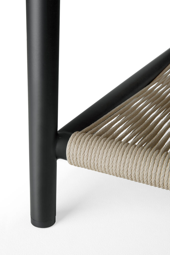 Gros plan d'un pied de chaise en métal noir et d'un coin d'assise avec une corde beige étroitement tissée, complétant parfaitement la table basse d'extérieur Corbey dans un cadre élégant.