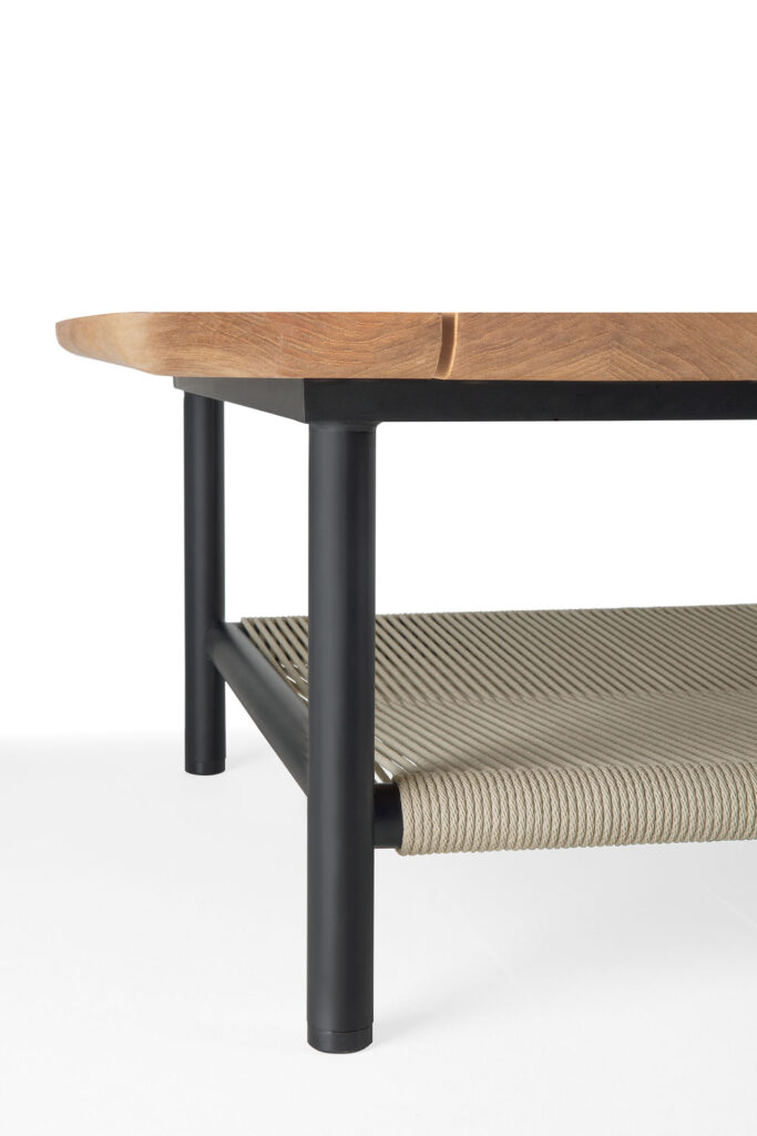 Gros plan de la table basse d'extérieur Corbey, mettant en valeur son plateau en bois, son cadre en métal noir et son étagère en corde sur un fond blanc uni.