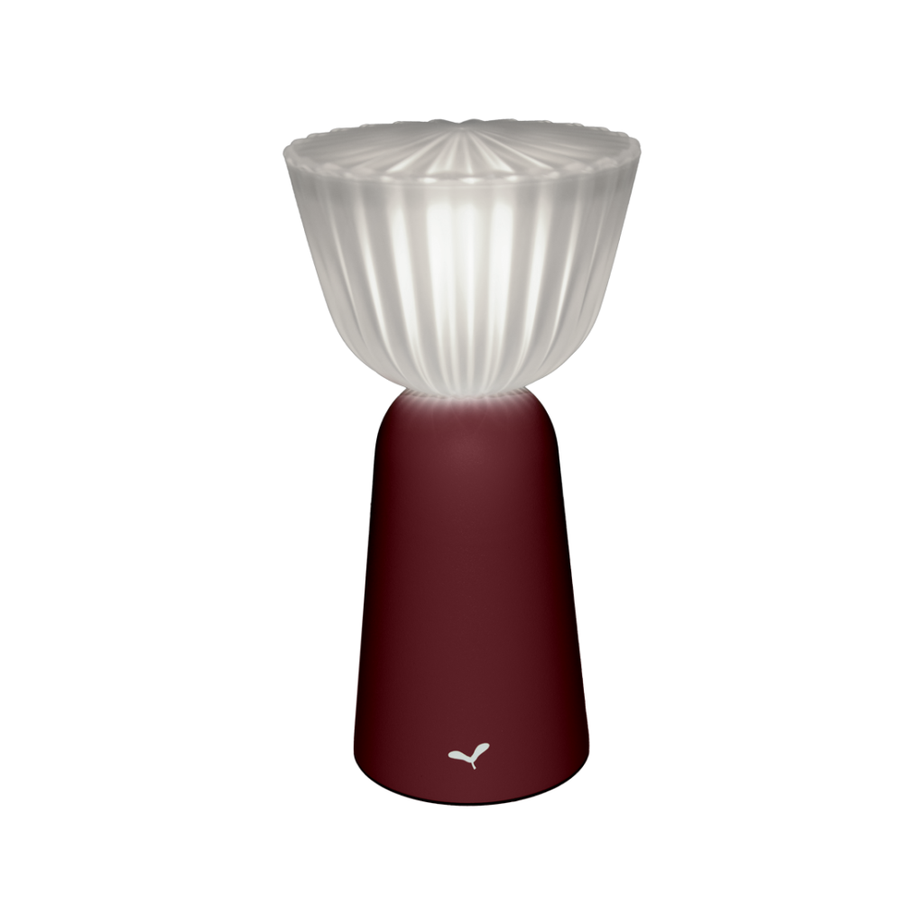 Présentation de la Lampe Swiing : une lampe de table moderne dotée d'un abat-jour translucide et cannelé perché élégamment sur une base conique cerise noire, le tout sur un fond rose saisissant.