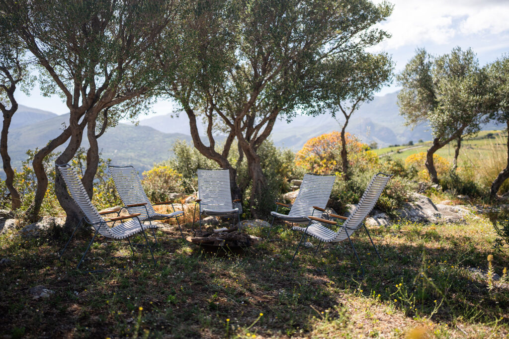 Cinq chaises longues CLICK disposées en cercle sous les arbres, avec une vue panoramique sur la montagne en arrière-plan.