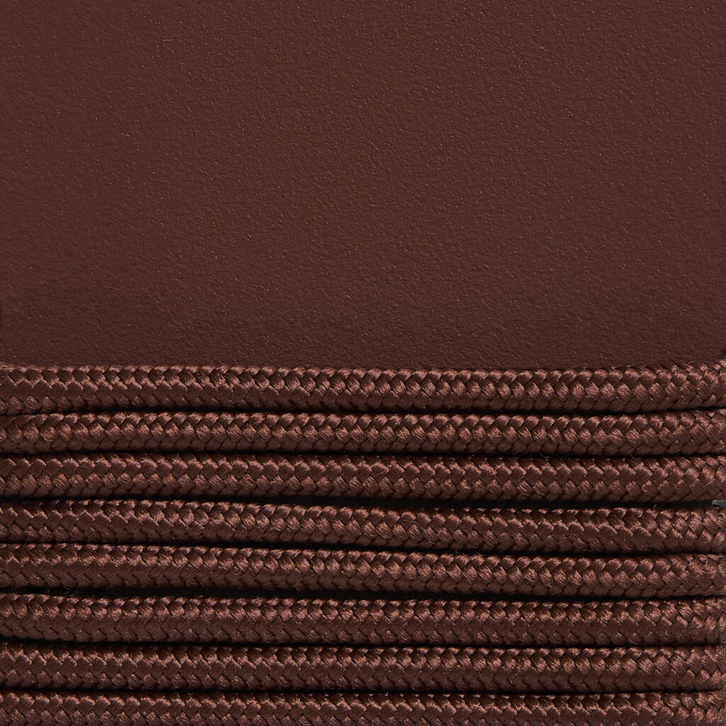 Gros plan d'une texture tressée marron empilée horizontalement contre la surface lisse, rappelant le design élégant de la chaise longue Palissade CORD.
