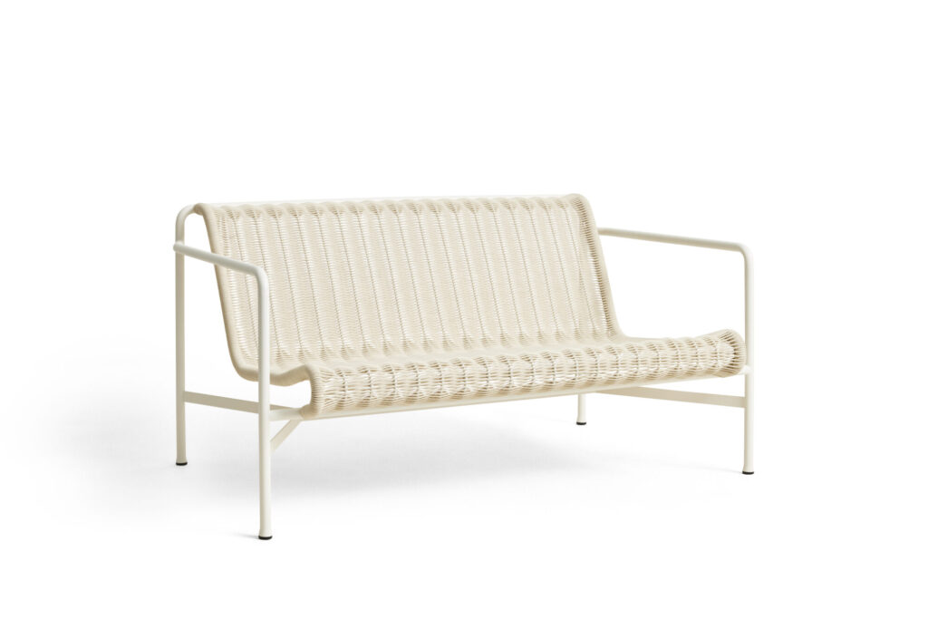 Un canapé de salon Palissade CORD blanc crème avec un motif tissé blanc sur sa structure en métal, doté d'accoudoirs ouverts, se dresse élégamment sur un fond blanc immaculé.